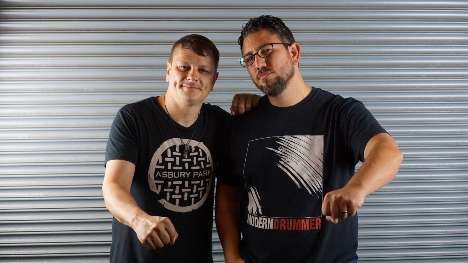 Miguel with Ray Luzier, standing in front of a metal shutter.